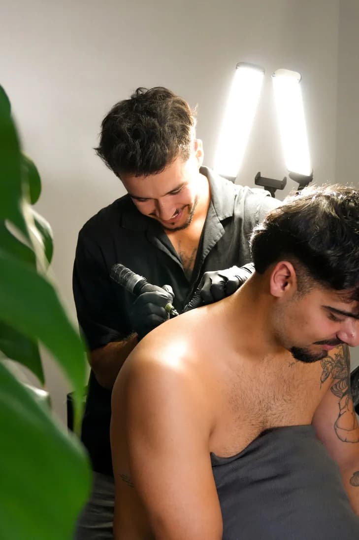 Daniel a tatuar o ombro de um cliente.