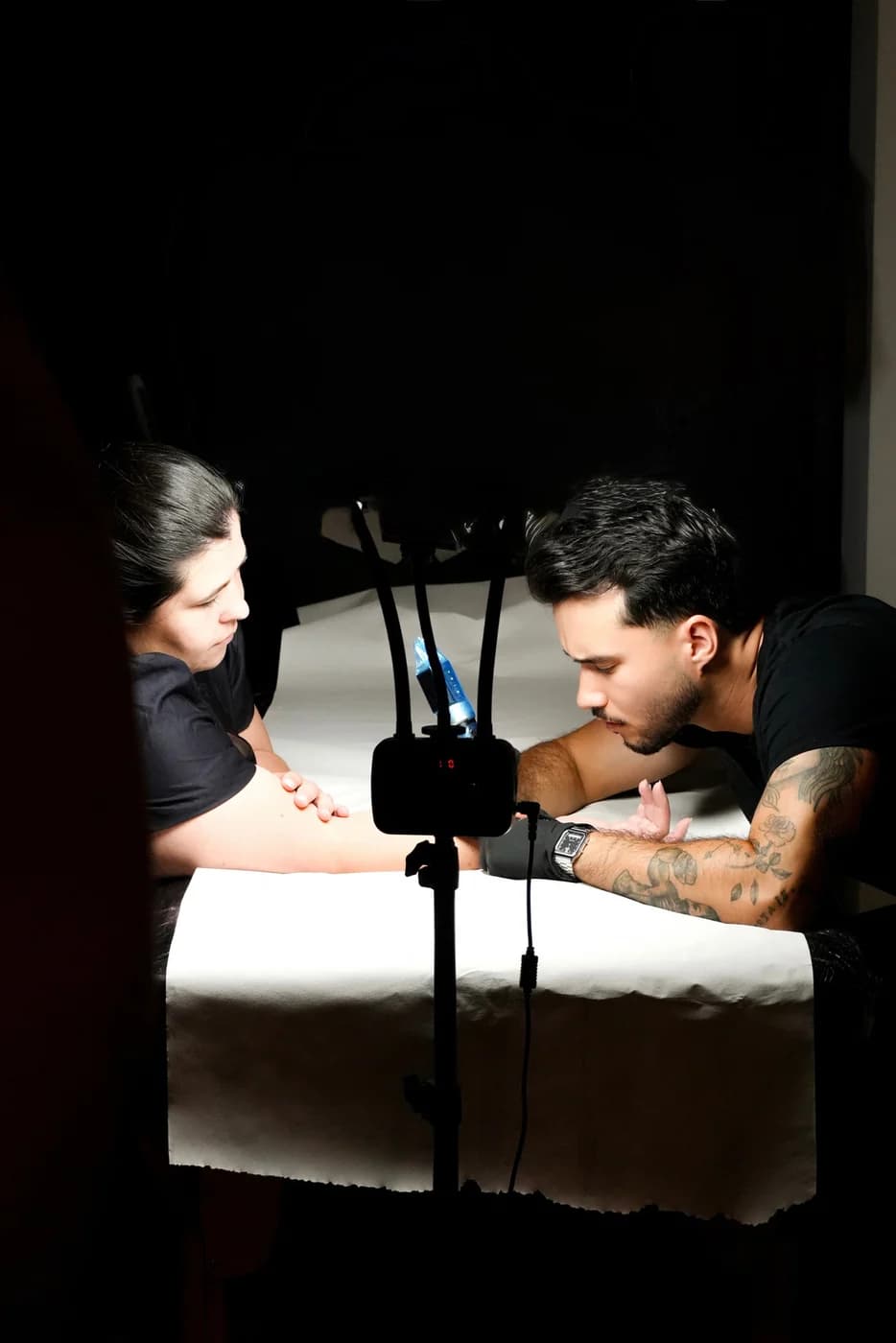 Daniel a tatuar um cliente, com a luz de trabalho sobre a marquesa.